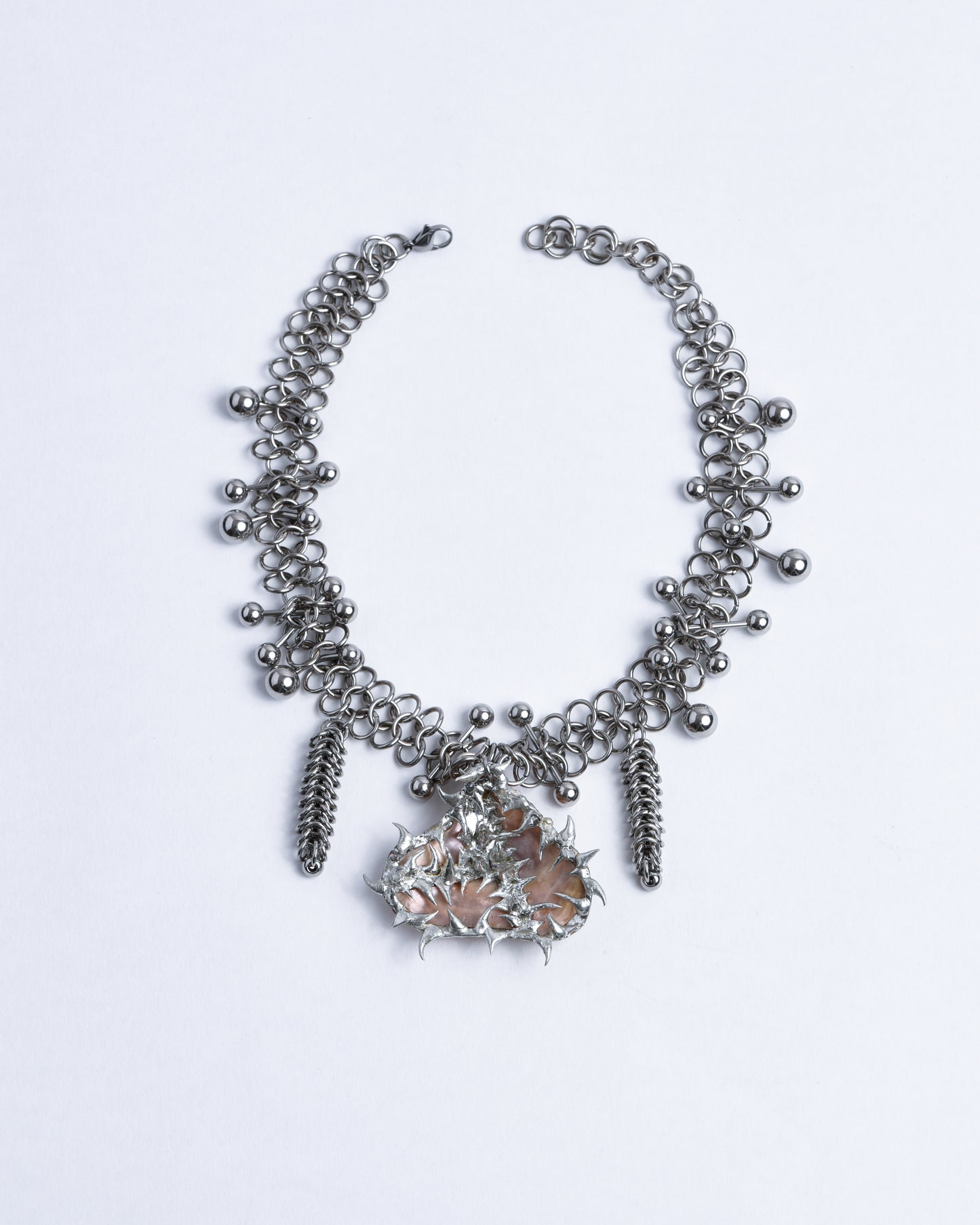 Silver chainmail choker piercings. Sea shell pendant with pinkish mother of pearl from adorned with silver spikes