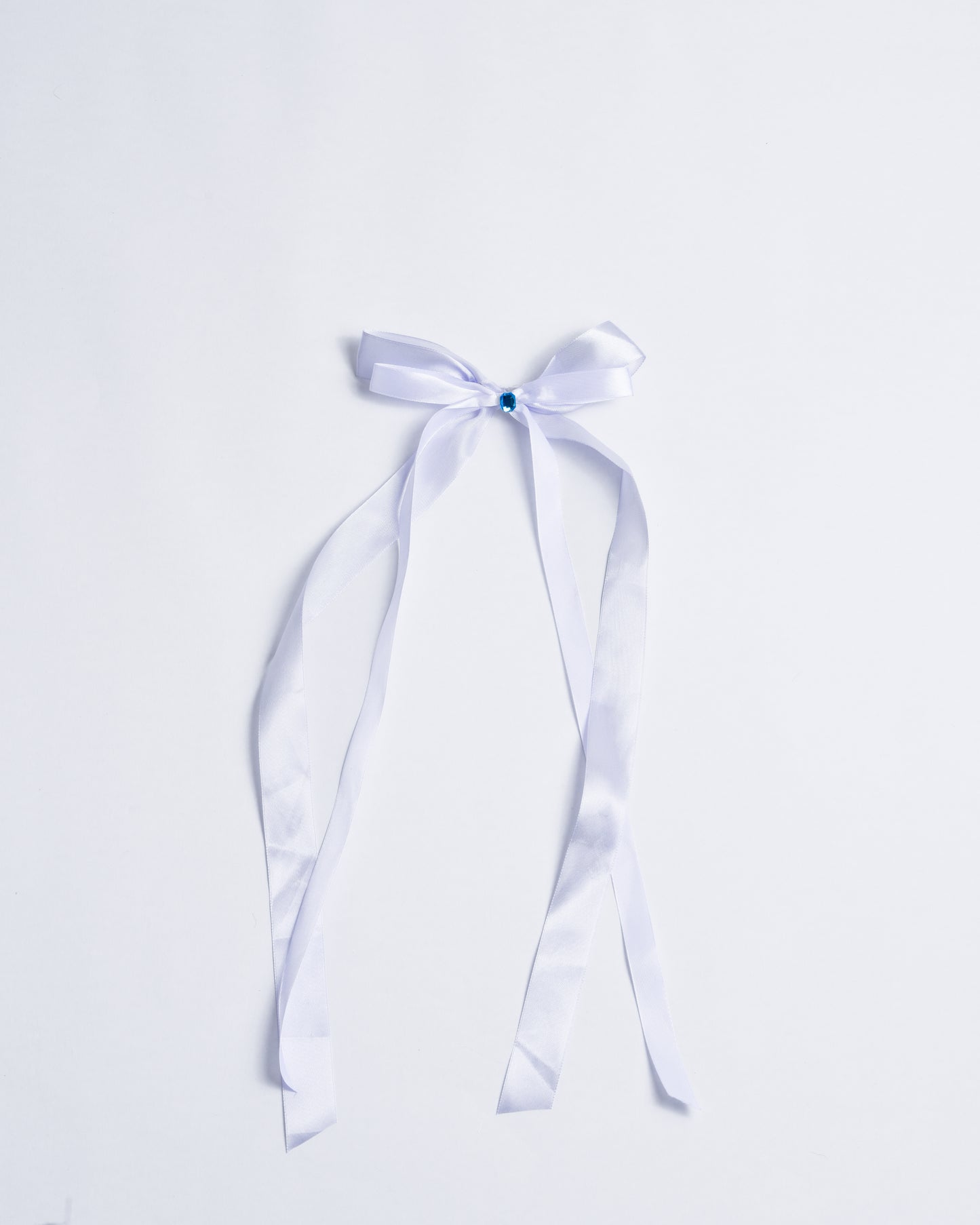 Blue fabric bow with a small plastic crystal, fixed onto gold metal pins.