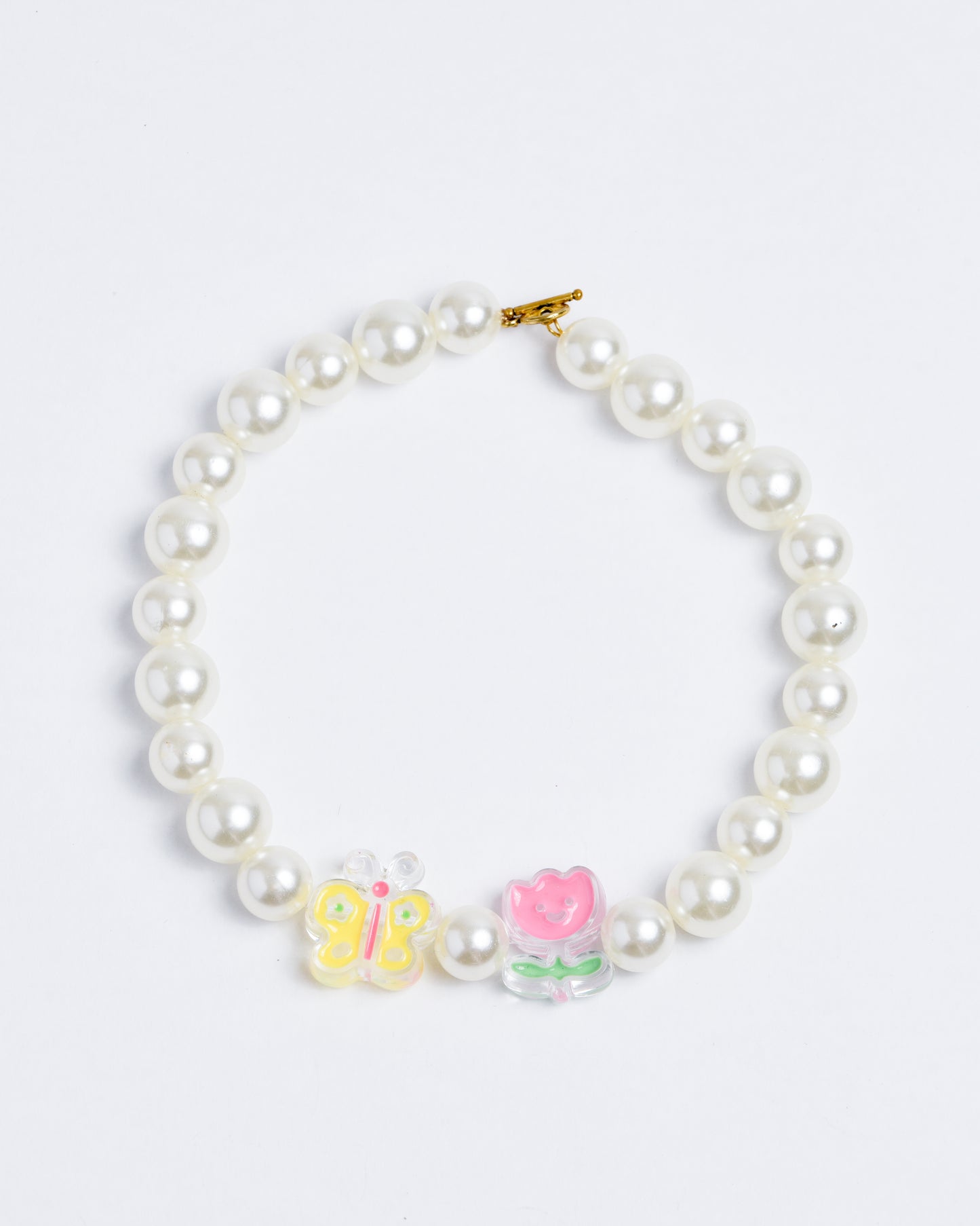 Large plastic pearls on a nylon cord with gold copper closures. Tulip and butterfly beads dominate the design.