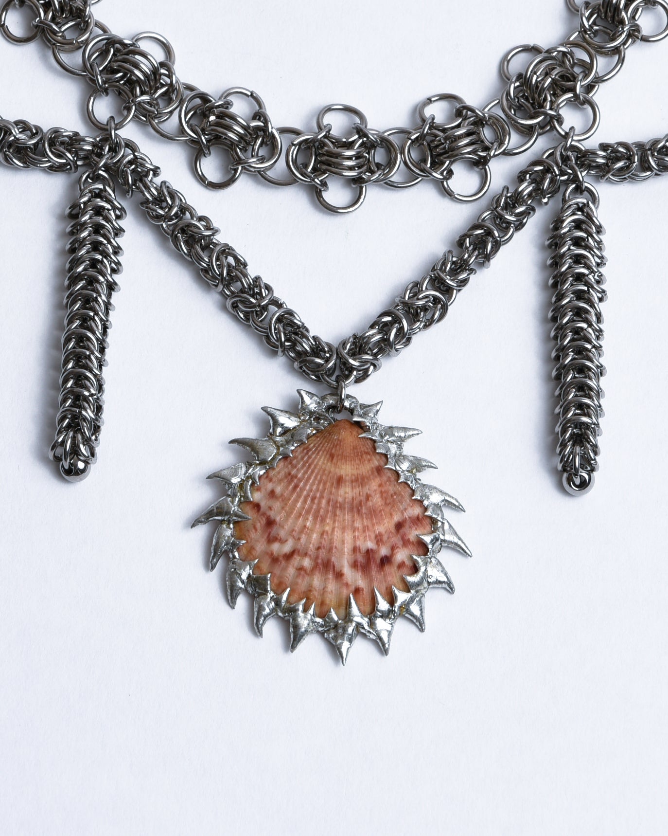 Closeup of red scallop shell pendant with silver spikes