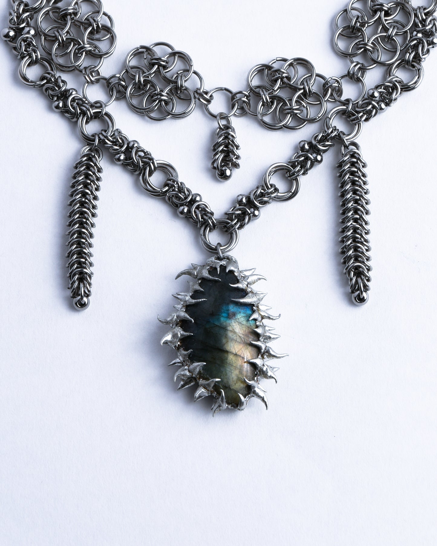 Closeup of pendant which is blue green labradorite with silver spikes