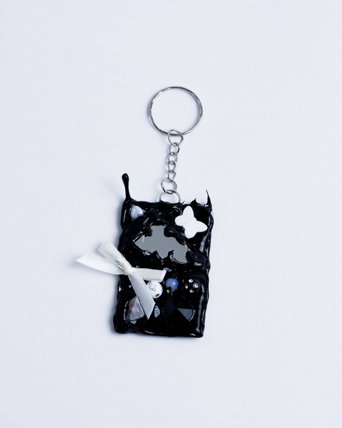 Black hot glue frame with beads pearls and little fabric bows to surround the broken mirror piece. Stainless steel rings are the keychain part holding the piece together.