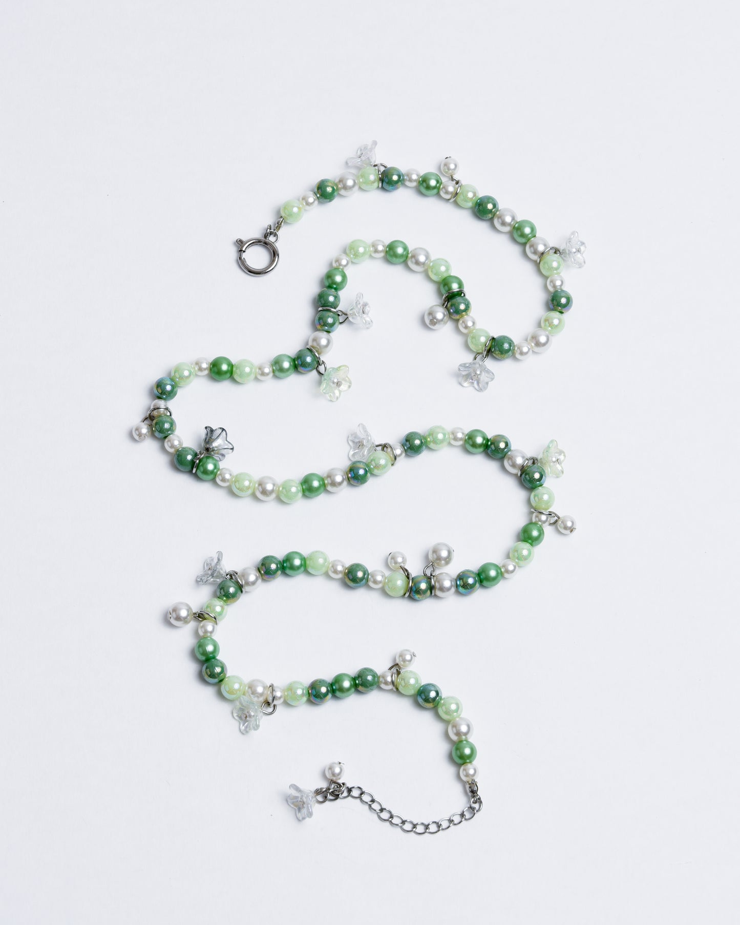 Green shiny plastic pearls combined with transparent plastic flower heads on an elastic nylon cord, featuring silver copper closures.