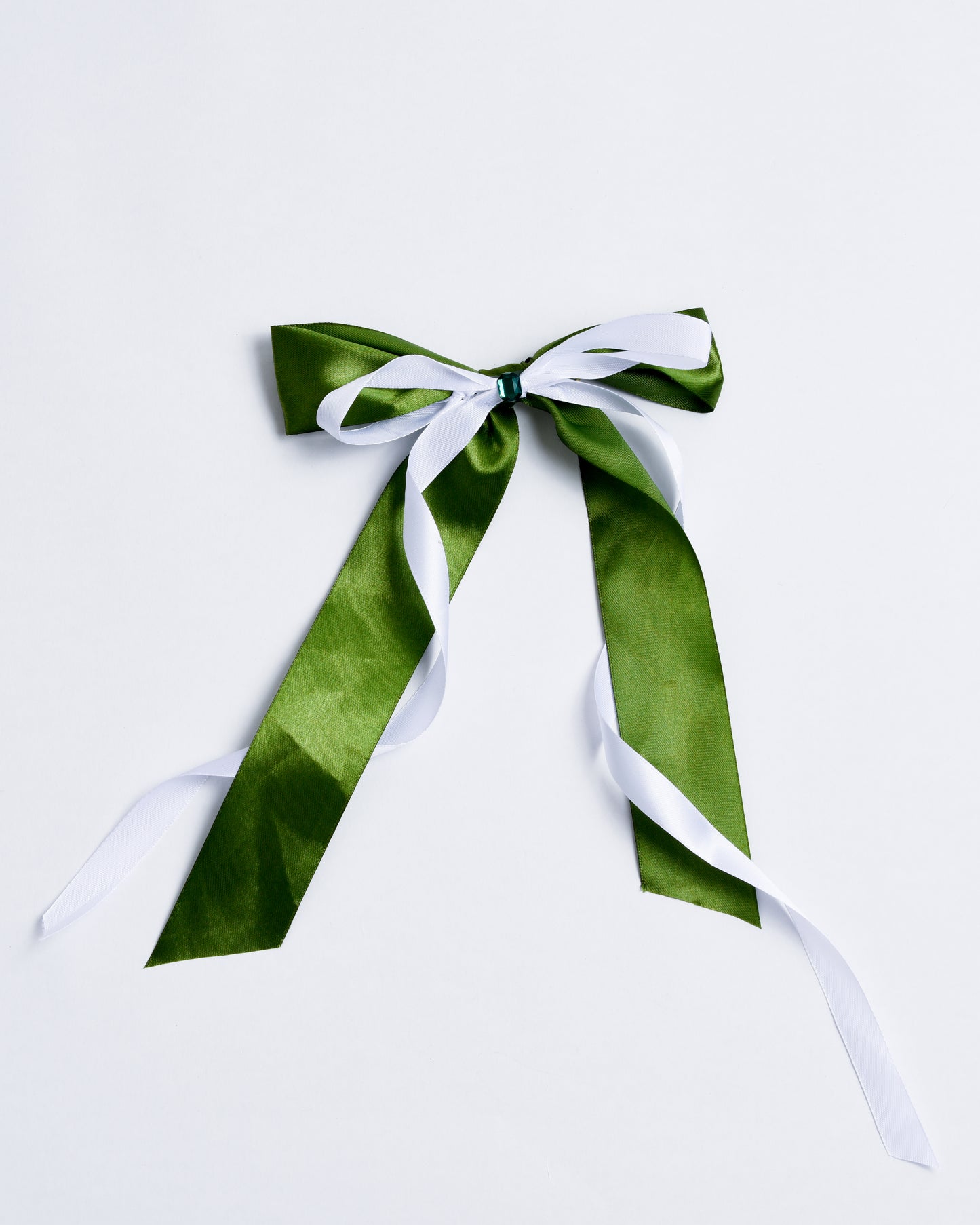Green fabric bow with a small plastic crystal, fixed onto gold metal pins.