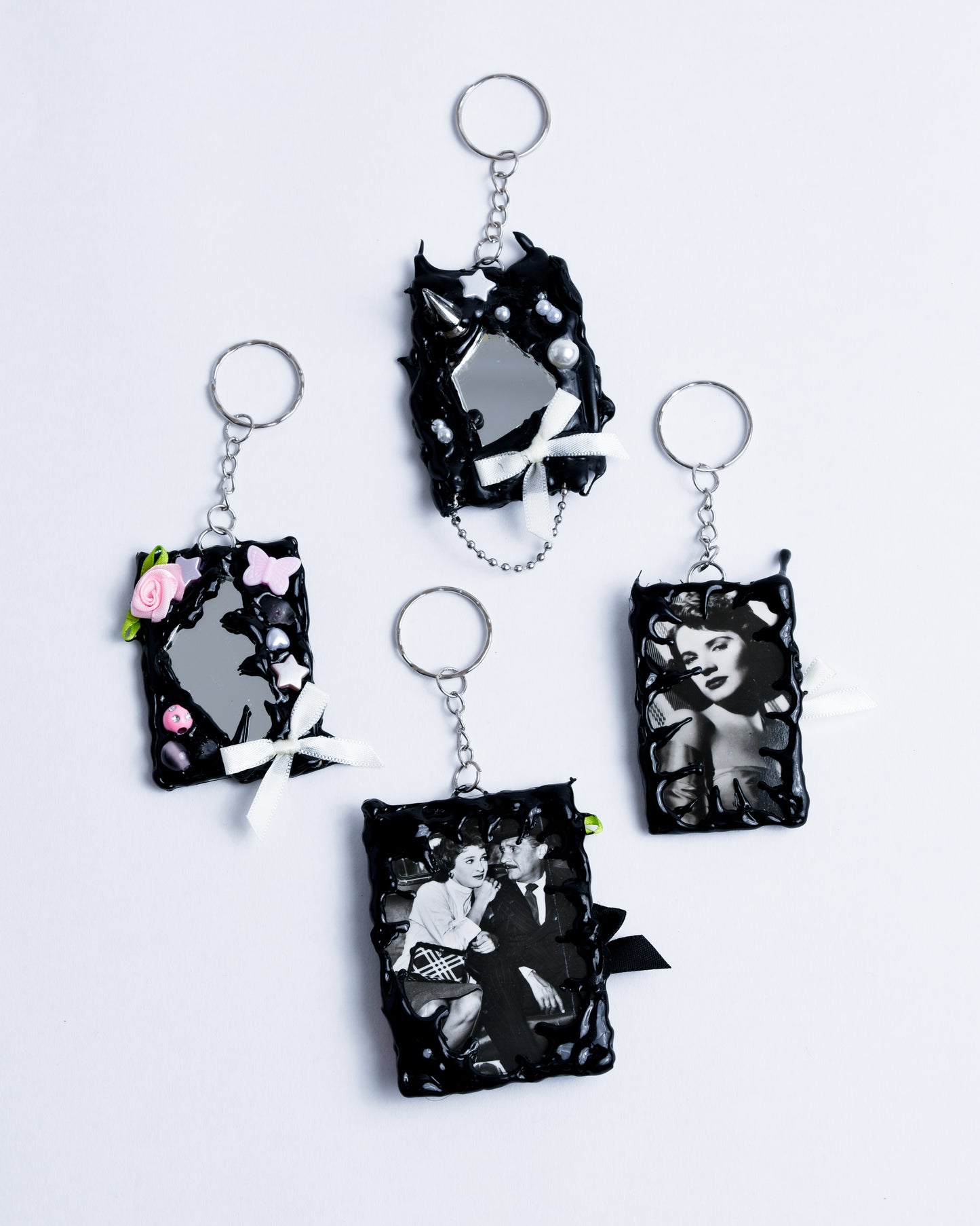 4 keychains with old black and white pictures of movie stars, black rectangle with pearls and bows