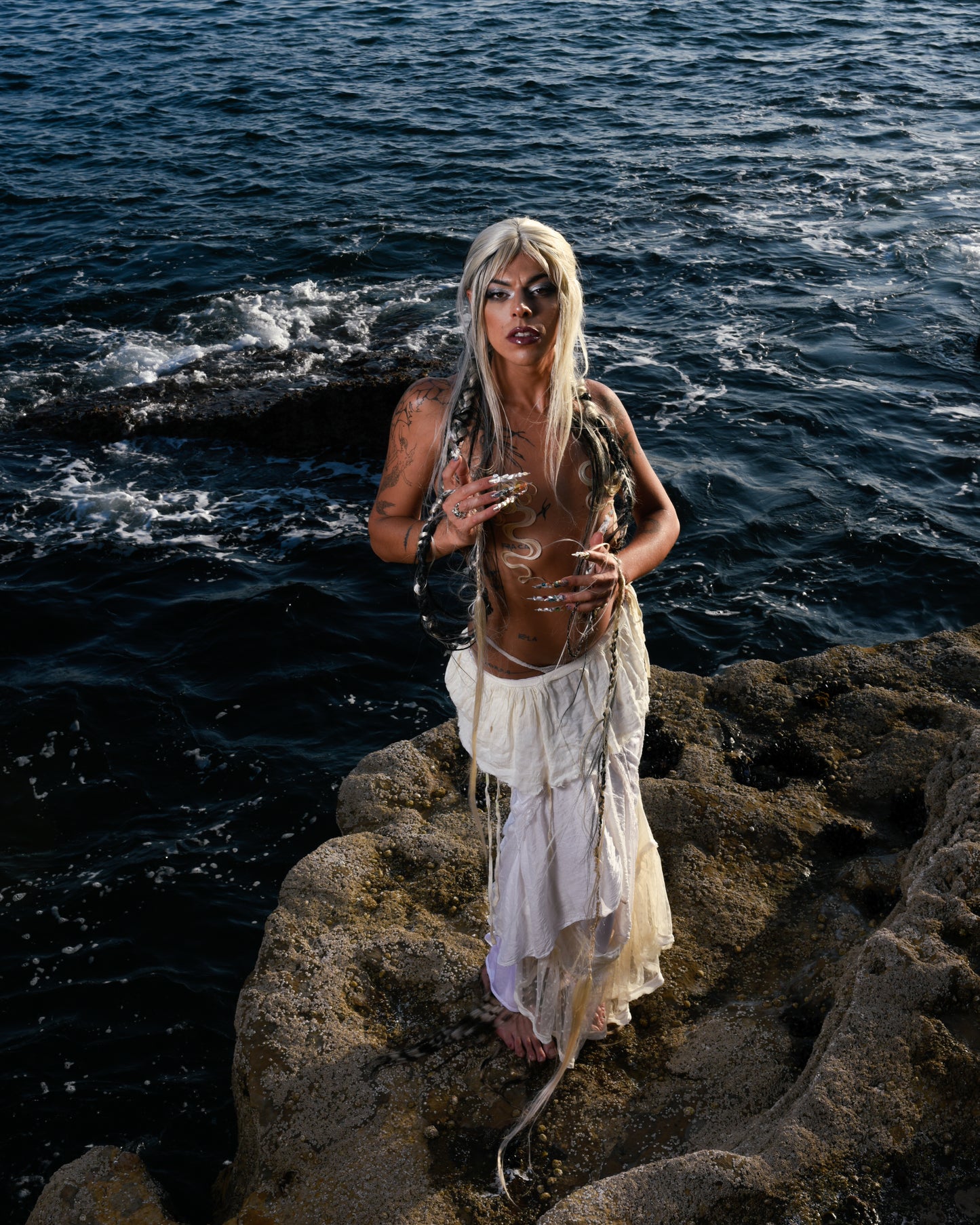 model standing on rock with ocean in background wearing wig zaya