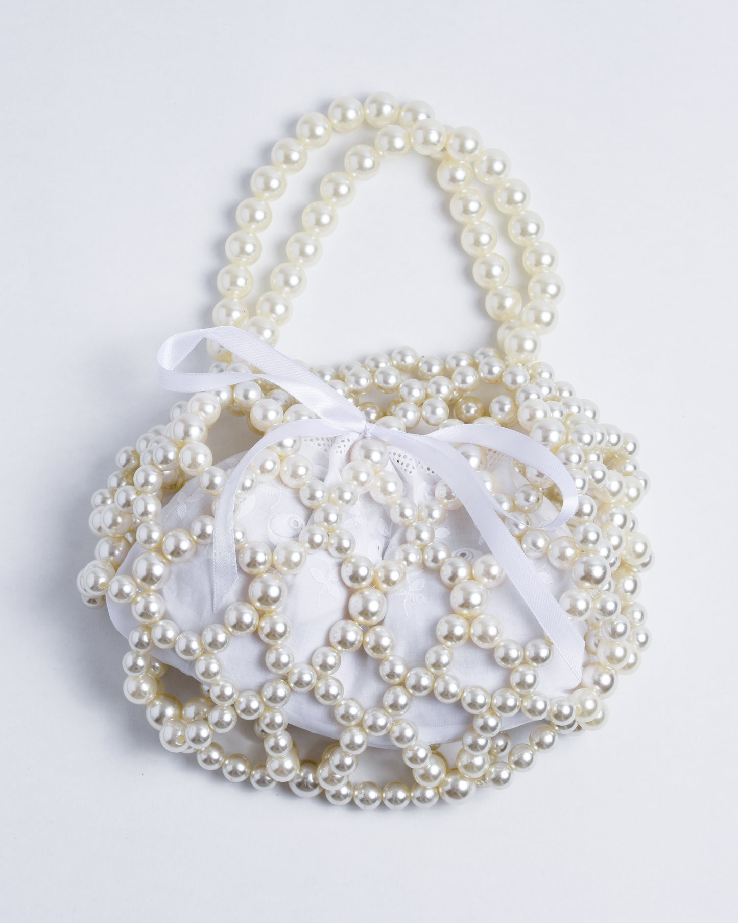 Large white plastic pearls woven together with strong nylon cord. The inside of the pearl bag features a small, closable fabric pouch made from self-sued white lace.