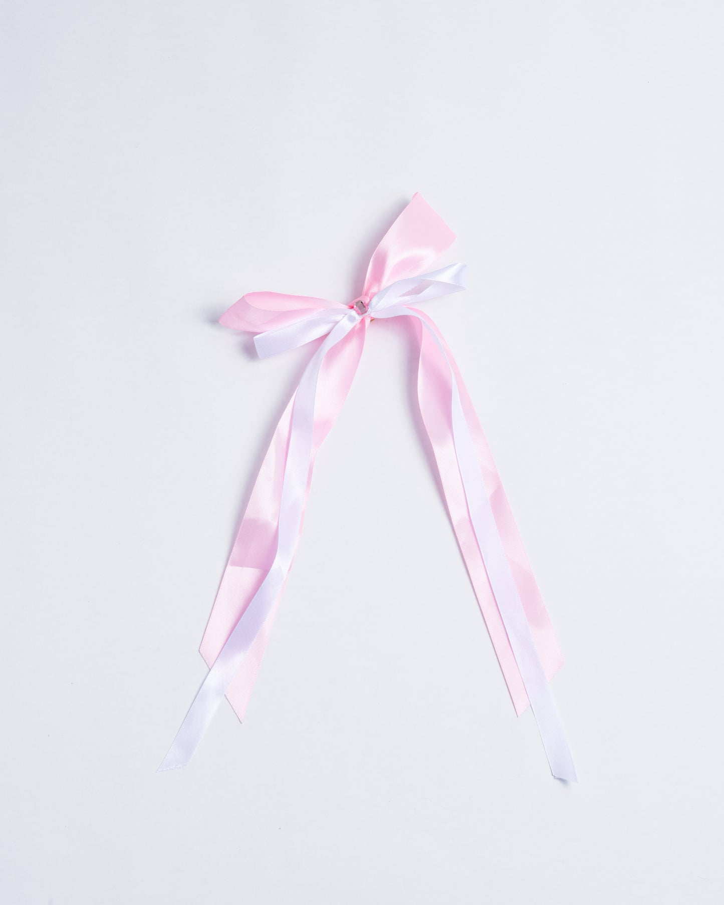 Pink fabric bow with a small plastic crystal, fixed onto gold metal pins.