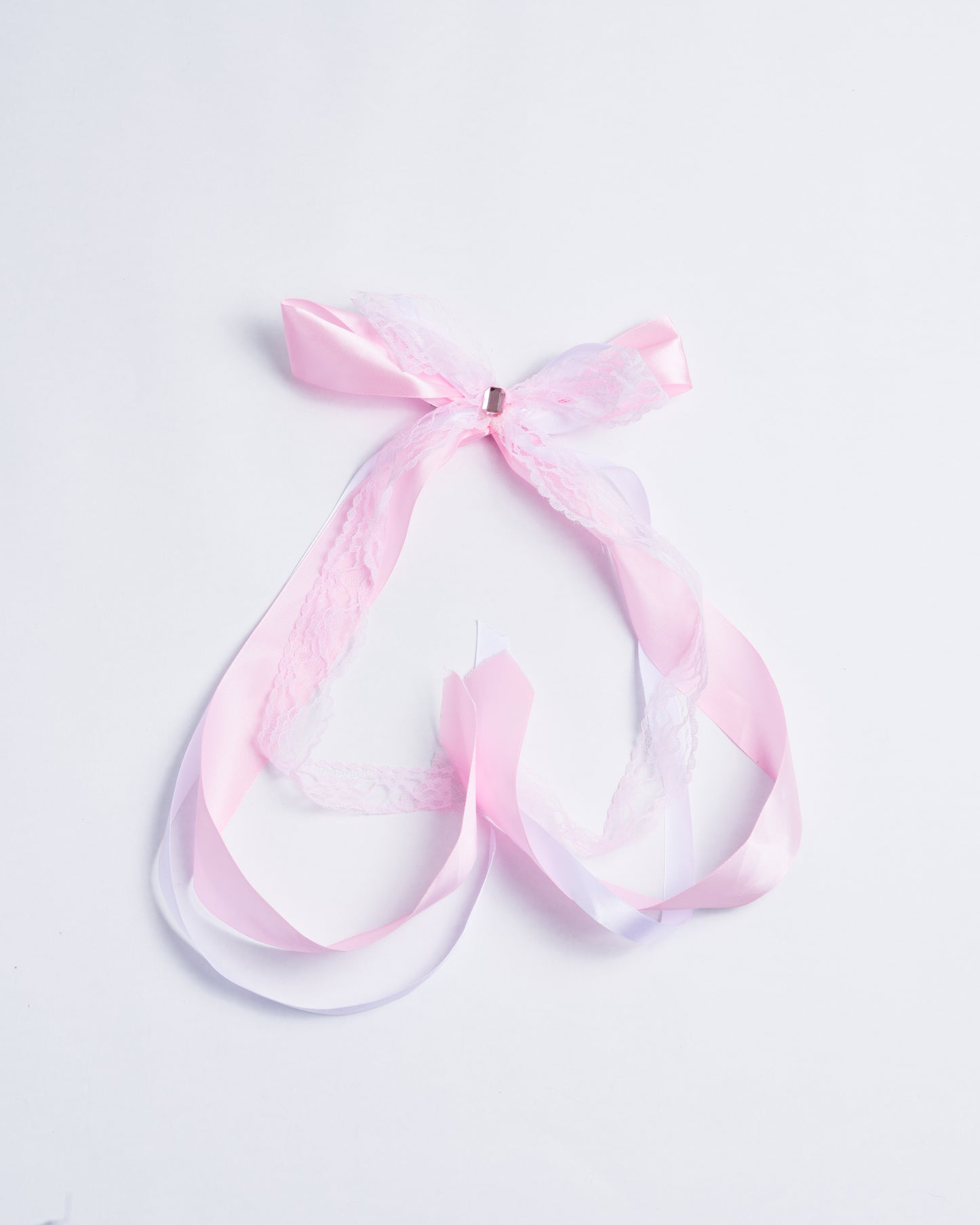 Pink fabric bow with a pink lace overlay and a plastic crystal, fixed onto a silver copper clip.