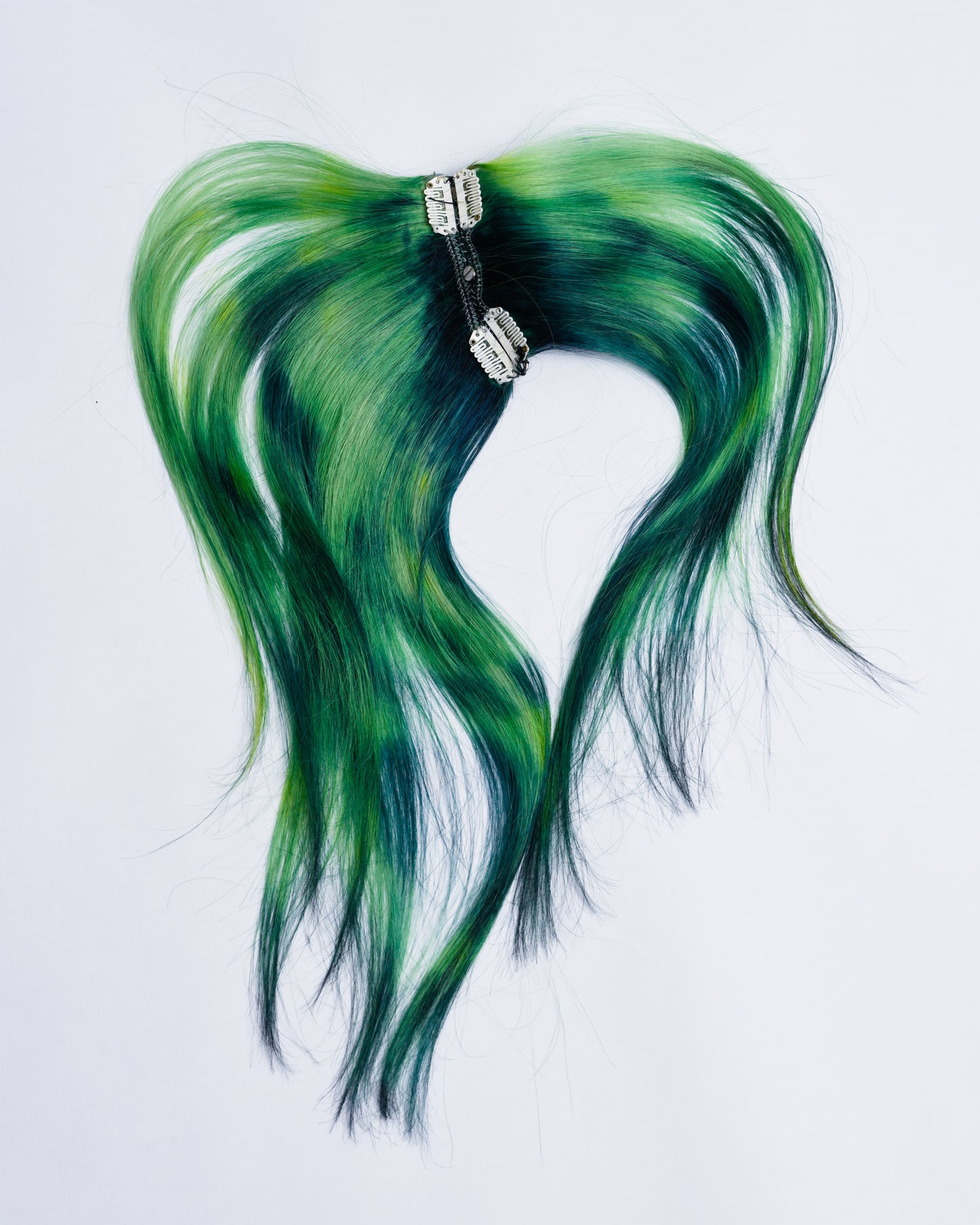 backside of dark green hair extensions with light green and yellow highlights the extensions are sewed together with chains and metal spikes. On the inside it’s 6 clips to attach the hairpiece on the hair