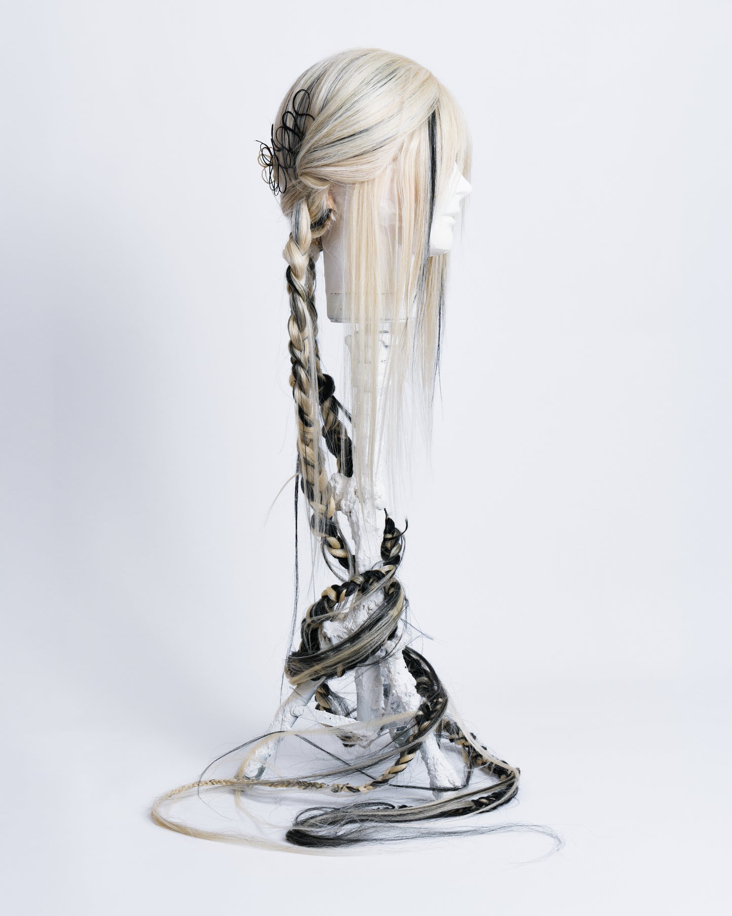 side of Light blonde synthetic wig with black highlights short curtain bangs in the back starting 2 braids there are 2 hair art pieces 2 handcrafted black and blonde hair flowers with a litle black water wave and then two 1,35 long braids with a lot of long hair coming out