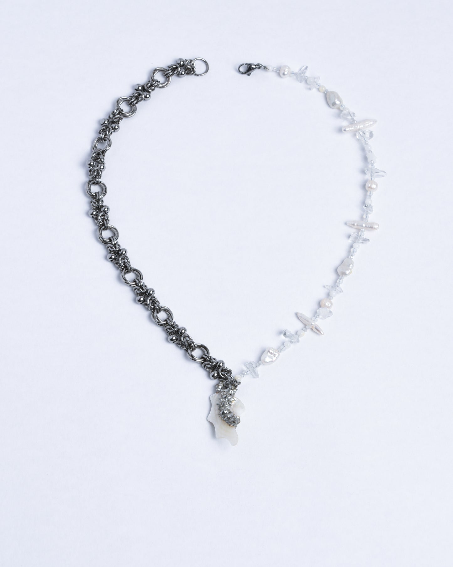 Half of the necklace is silver stainless steel chainmail, other half is a mix of pearls, crystals and biwa pearls. The pendand is a polished sea shell with spikes and in the middle of the pendant are silver soft solder spikes