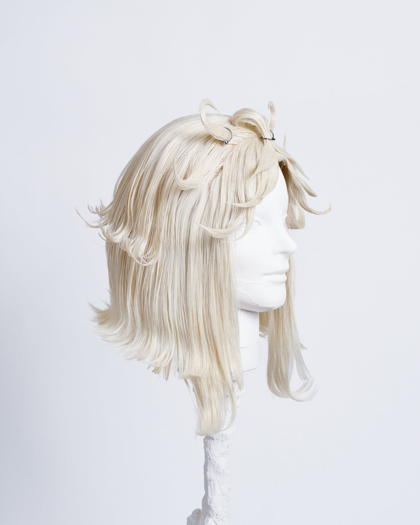 side of white 30cm long bob cut wig with styled spikes in the fringe inspired by a flower , highlighted with metal rings .